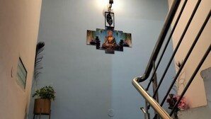 A staircase with a wall-mounted artwork of a seated figure, a potted plant, and a metal handrail.