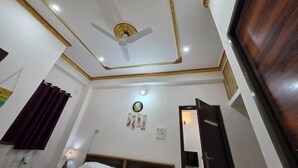A room with a ceiling fan, a bed, a bedside table, a lamp, and a door.