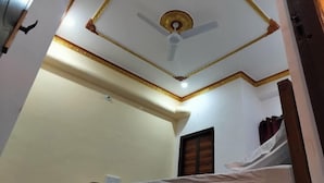A room with a bed, a ceiling fan, and a window with curtains.
