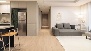 A modern apartment with a kitchenette, a grey sofa, and a minimalist design. - Mount Air Condo (Seoul)