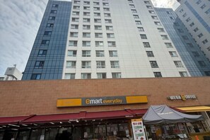 A building with a 'emart everyday' sign, a 'Miller Coffee' sign, and a tent-like structure in front. - Mount Air Condo (Seoul)