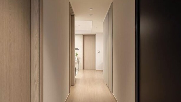 A hallway with wooden flooring and walls, leading to a room with a door. - Mount Air Condo (Seoul)