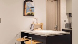A kitchen with a small island, two bar stools, a wooden door, and a window with a view of mountains. - Mount Air Condo (Seoul)