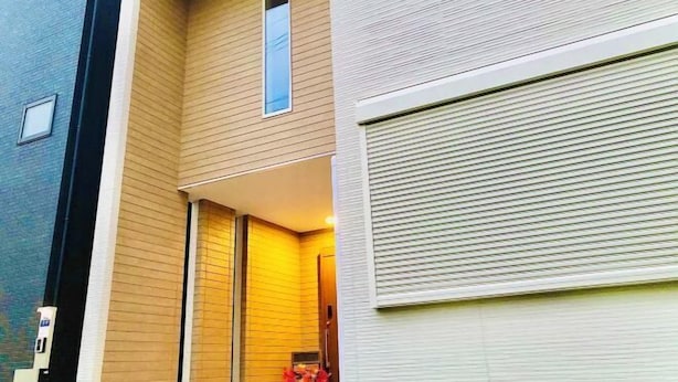 A multi-story building with a beige exterior, a visible window, and a closed shutter on the right side. - Kannosu NO.1 (Osaka)