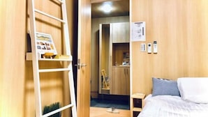 A hotel room with a bed, a small bedside table, a wardrobe, and a ladder leading to a loft area. - Kannosu NO.1 (Osaka)