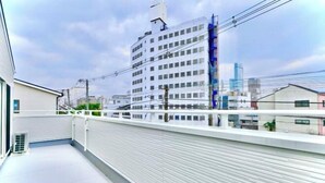 A rooftop terrace with a view of a cityscape, including a tall building and power lines. - Kannosu NO.1 (Osaka)