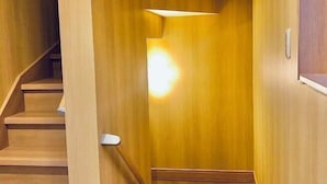 A wooden staircase with a light fixture on the wall. - Kannosu NO.1 (Osaka)