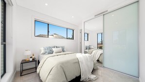 Camera moderna con un letto grande, un comodino, uno specchio e vista sull'esterno.