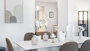 Un'elegante sala da pranzo moderna con tavolo e sedie bianche, arricchita da vasi e candele decorative.