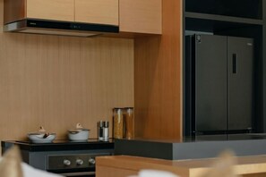 Une cuisine moderne avec un poêle noir, des armoires en bois et un réfrigérateur en acier inoxydable.