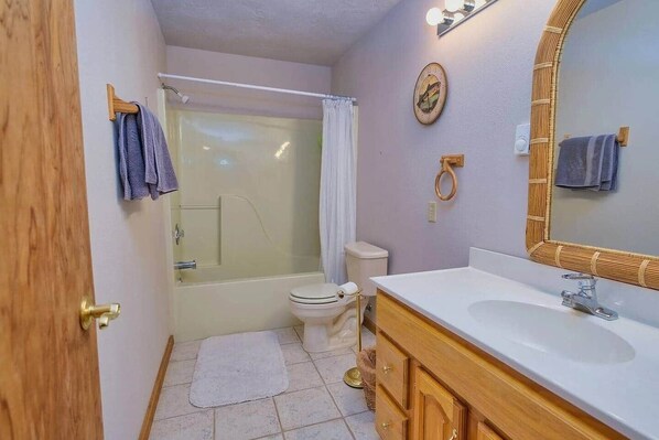 A bathroom with a bathtub, toilet, and vanity with a mirror. - River Bend Retreat (Bonneville County)