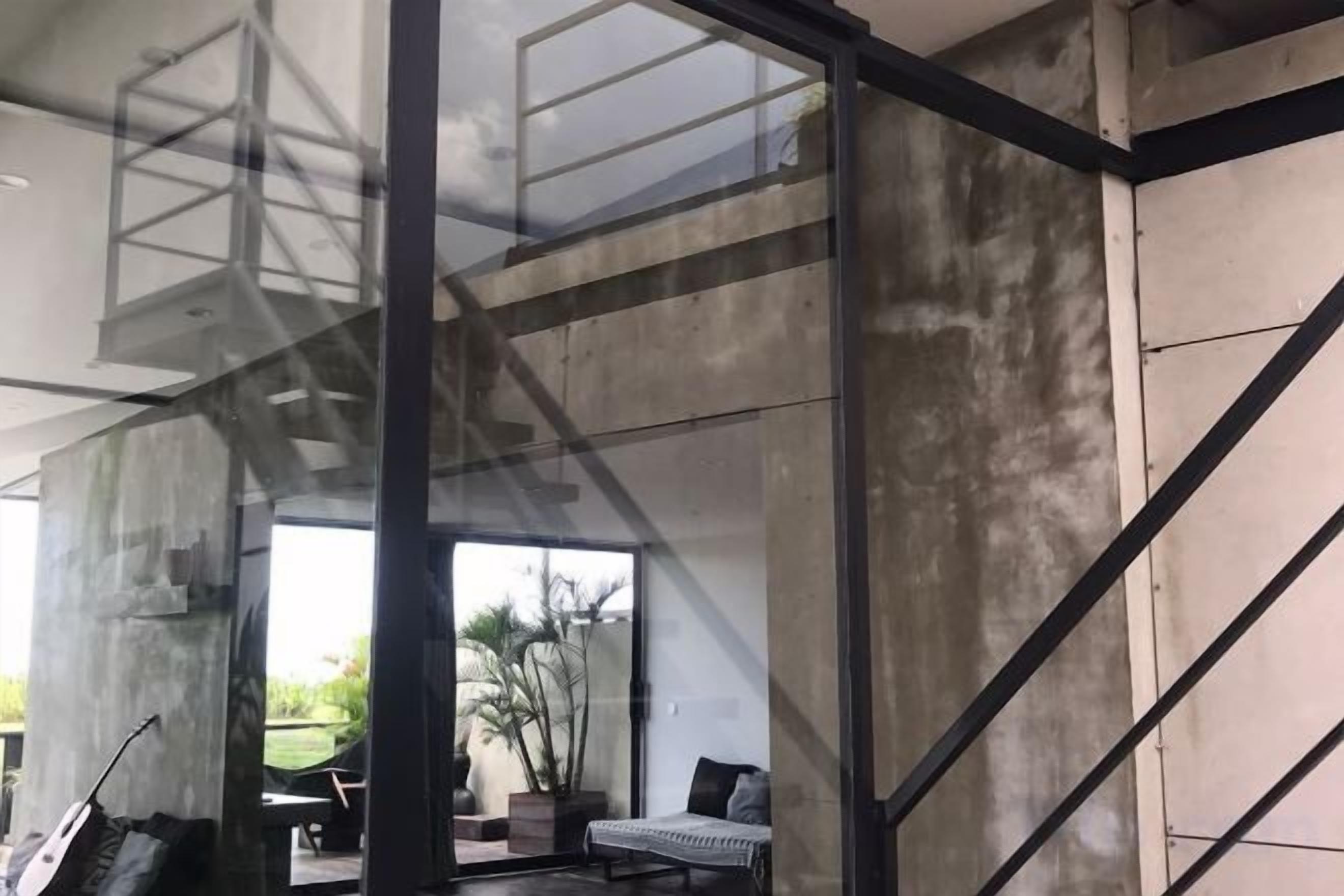 A modern interior with a staircase, concrete walls, and a view of the outdoors.