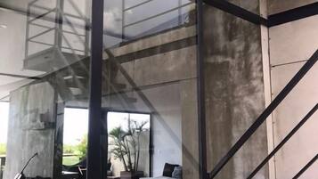 A modern interior with a staircase, concrete walls, and a view of the outdoors.