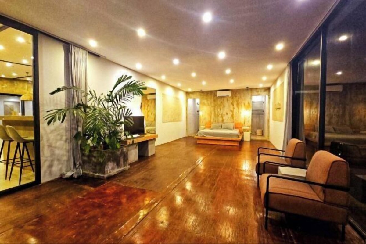 Une pièce spacieuse avec un plancher en bois, un canapé et un coin repas avec des chaises.