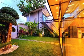A modern building with a staircase leading to an upper level, a well-maintained lawn, and a glass facade.