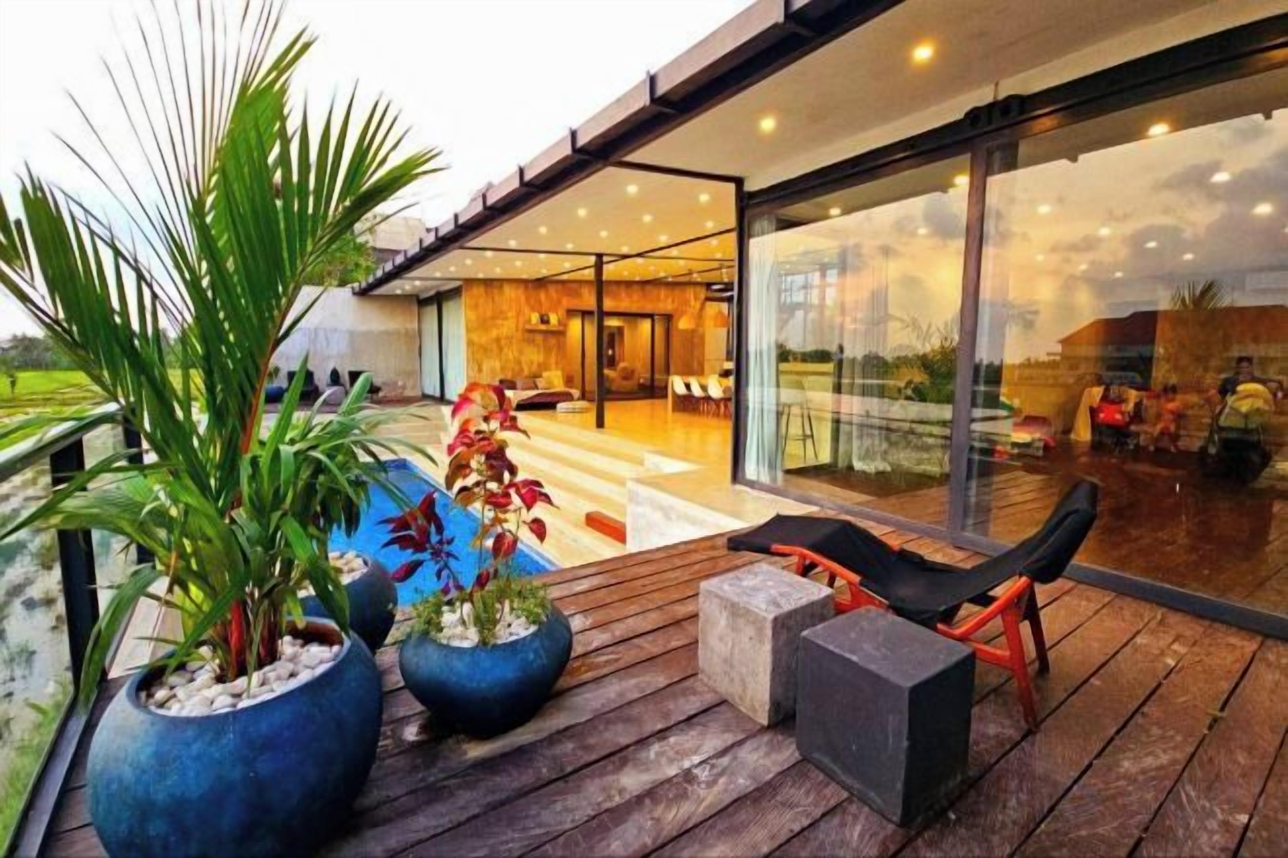 A modern outdoor area with a wooden deck, seating, and potted plants.