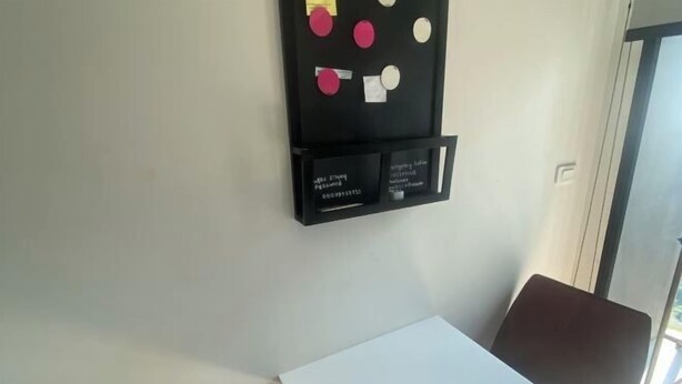 A room with a white table, a blackboard with papers, and a window. - BRAND New Sukhumvit Condo Cozy BTS (Bangkok)