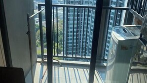 A balcony with a view of high-rise buildings, a metal railing, and a piece of exercise equipment. - BRAND New Sukhumvit Condo Cozy BTS (Bangkok)