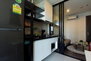 Una cocina compacta con refrigerador, gabinetes y cafetera.