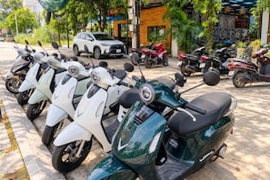 A row of parked scooters and a car in an outdoor parking area. - Tam Coc Mandala Homestay & Pool (Hoa Lu District)