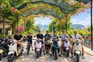 A group of people on scooters under a covered area with a view of mountains in the background. - Tam Coc Mandala Homestay & Pool (Hoa Lu District)