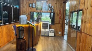 A wooden interior with a reception desk, air conditioning units, and framed artwork on the wall. - Tam Coc Mandala Villa (Hoa Lu District)