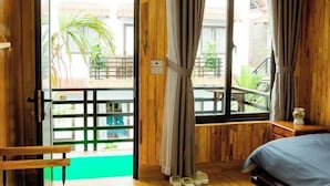 A wooden room with a bed, a small table, and a window with curtains. - Tam Coc Mandala Villa (Hoa Lu District)