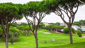 A golf course with trees, a golf cart, and a golfer. - BnB Homes Apartment with cozy Terrace & Swimming pool near the heart city (Albufeira)