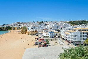A coastal town with a beach, buildings, and a clear sky. - BnB Homes Apartment with cozy Terrace & Swimming pool near the heart city (Albufeira)