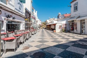 A cobblestone street with outdoor seating and buildings on either side. - BnB Homes Apartment with cozy Terrace & Swimming pool near the heart city (Albufeira)