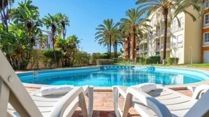 A swimming pool with white lounge chairs and palm trees. - BnB Homes Apartment with cozy Terrace & Swimming pool near the heart city (Albufeira)