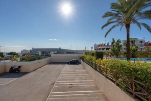A parking area with a car, palm trees, and buildings in the background. - BnB Homes Apartment with cozy Terrace & Swimming pool near the heart city (Albufeira)