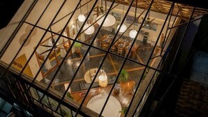 A dining area with tables and chairs, a central island, and hanging pendant lights. - Unique space: The Glass House (El Nido)
