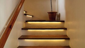A staircase with wooden steps and a wooden handrail, illuminated by under-cabinet lighting. - Unique space: The Glass House (El Nido)