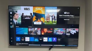 A flat-screen TV mounted on a wall above a black entertainment unit with two small white figurines on top. - Cutee Home in Prairie Pointe (Winnipeg)
