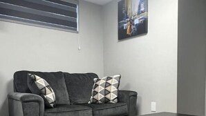A modern living room with a grey sofa, a black coffee table, and a fluffy rug. - Cutee Home in Prairie Pointe (Winnipeg)