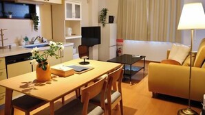 A compact living space with a dining table, sofa, and TV. - Orange House Tsuruhashi｜With Garage, Accommodates 8 People (Osaka)