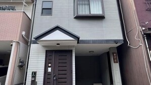 A two-story residential building with a front entrance, a small porch, and a visible mailbox. - Orange House Tsuruhashi｜With Garage, Accommodates 8 People (Osaka)