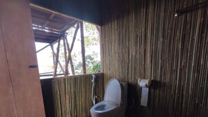 Een badkamer met bamboevloer en -wanden, een toilet en een douche.