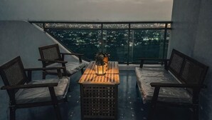 A balcony with a table, chairs, and a view of a cityscape at night. - 2 BR Penthouse w/ Wide Balcony and 7ft Billiards (San Fernando)