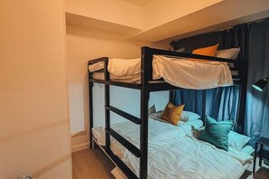 A bunk bed with white bedding and pillows, a desk with a lamp, and a window with curtains. - 2 BR Penthouse w/ Wide Balcony and 7ft Billiards (San Fernando)