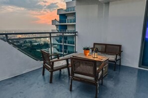 Un balcón con mesa y sillas, una planta en maceta y vistas de la ciudad.