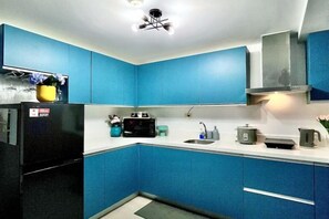 A kitchen with blue cabinets, a black refrigerator, a microwave, and a sink. - 2 BR Penthouse w/ Wide Balcony and 7ft Billiards (San Fernando)
