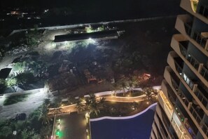 A nighttime view of a hotel with a pool, outdoor lighting, and a landscaped area with palm trees. - 2 BR Penthouse w/ Wide Balcony and 7ft Billiards (San Fernando)