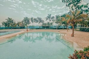 Ein Poolbereich mit Palmen und blauem Himmel.