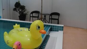 A pool with inflatable ducks, a potted plant, and two chairs. - Sroysuwan Pool villa (Khanom)