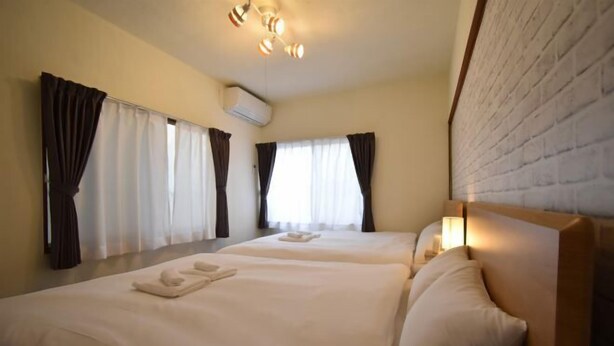A hotel room with two beds, a brick wall, and a ceiling fan. - Bunka 1 chome (Tokyo)