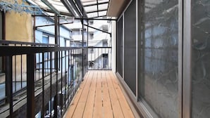 A narrow balcony with a wooden floor, metal railing, and a glass door. - Bunka 1 chome (Tokyo)