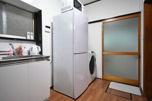 A compact kitchen with a refrigerator, washing machine, and a window above the sink. - Bunka 1 chome (Tokyo)