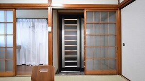 A traditional Japanese room with sliding doors, tatami flooring, and a wooden chair. - Bunka 1 chome (Tokyo)